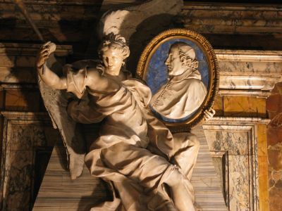 monumento funebre del Card. Fabrizio Paolucci
di Pietro Bracci (1729): La fama regge il ritratto del Cardinale rappresentato entro un ovale di marmo bianco su sfondo di lapislazzuli
